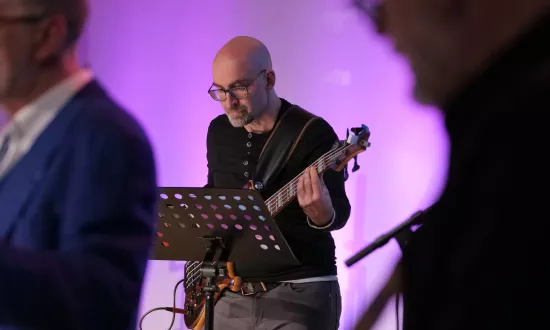 Bassist vor lilafarbenem Hintergrund auf einer Bühne