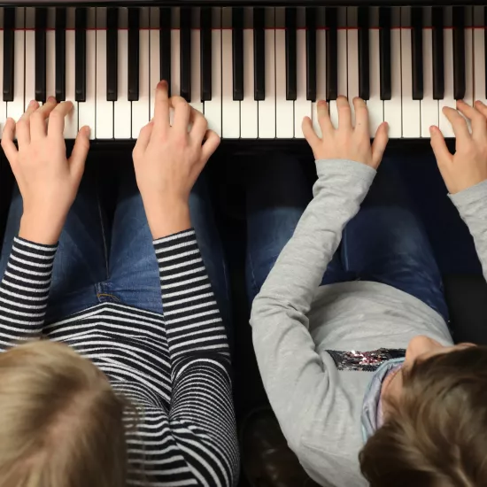 Zwei Kinder spielen gemeinsam am Klavier