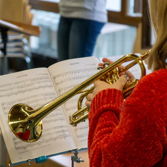 Eine Frau von hinten, die vor einem Notenständer Trompete spielt